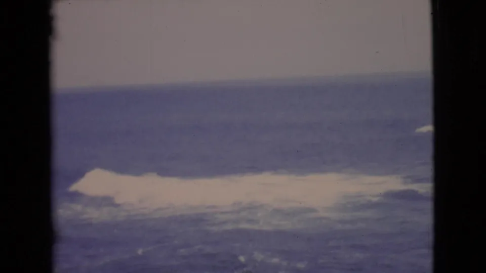 1968 San Diego County home-movie frame of ocean water, bright surf, pale sky, and soft color-faded 8mm texture.