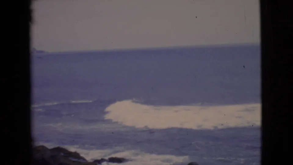 1968 8mm coastal footage shows white surf rolling across the ocean with a dark film-frame divider at center.