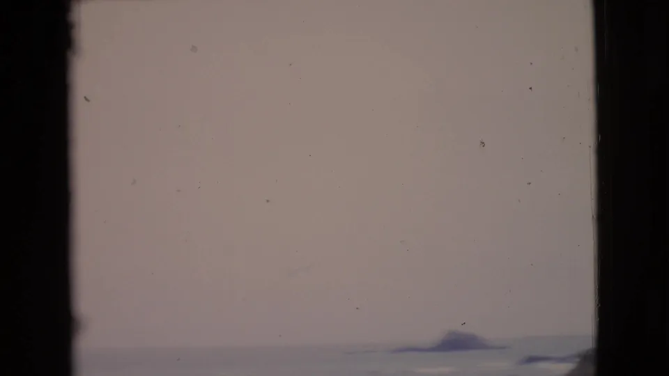 Faded 8mm view of the San Diego County ocean horizon, with a small distant ship-like shape or offshore form near the waterline.