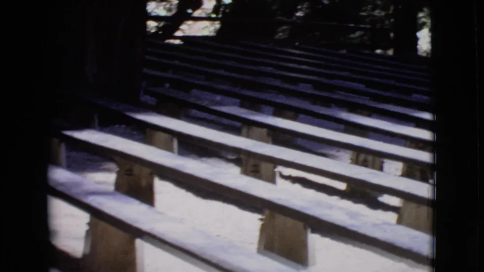 Final 1968 San Diego County frame with empty tiered benches angled through a shaded outdoor amphitheater-like space.