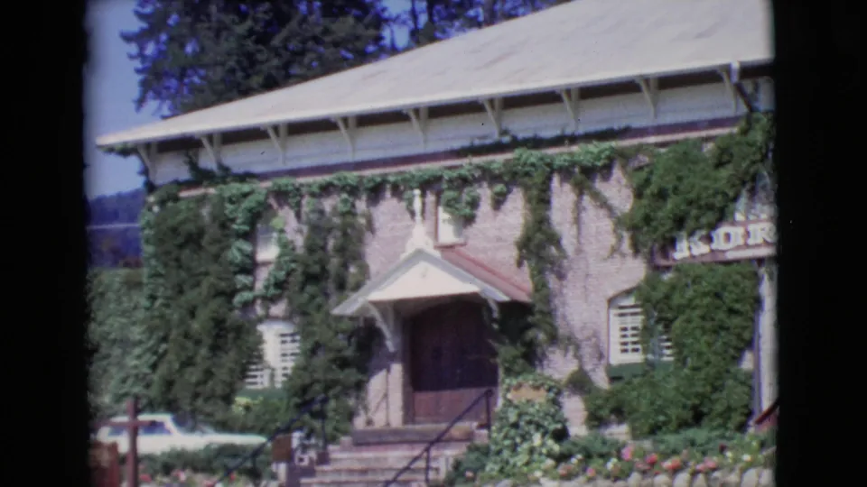 Closer 1968 San Diego County view of an ivy-covered brick building entrance, exterior steps, windows, flowers, and partial sign lettering.