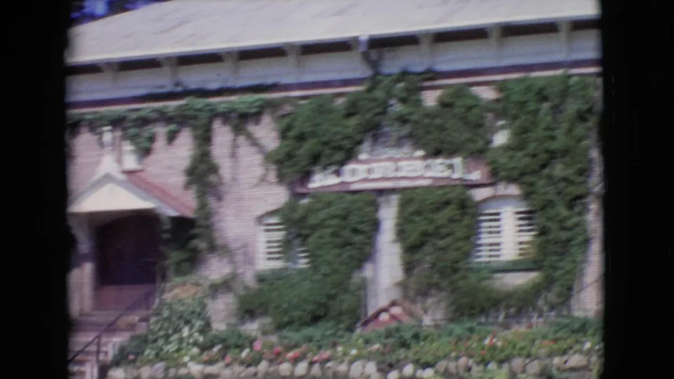 Final frame of the 1968 San Diego County clip showing the ivy-covered facade, entrance steps, windows, garden beds, and a visible Korbel sign.