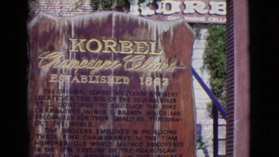 1968 8mm San Diego County close view of the Korbel Champagne Cellars sign, with established date text, brickwork, steps, and railing visible.