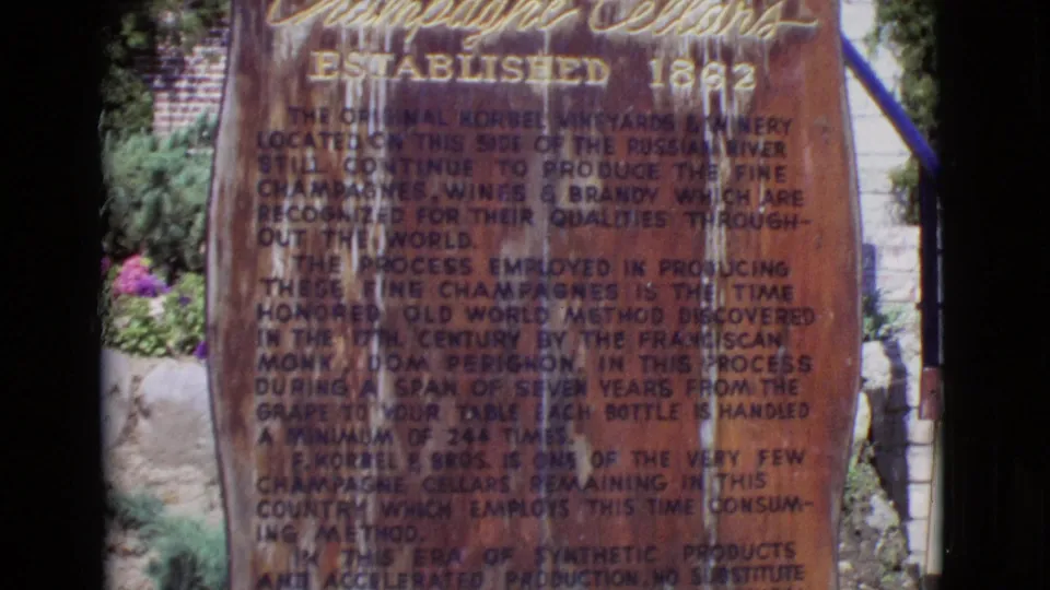 1968 8mm frame from San Diego County showing a weathered winery history monument with faded engraved text and surrounding stonework.