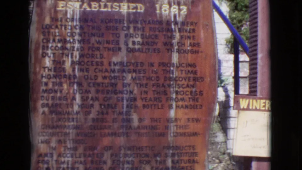 Handheld 1968 8mm view of the winery monument, with Korbel text visible and a partial winery sign at the right edge.
