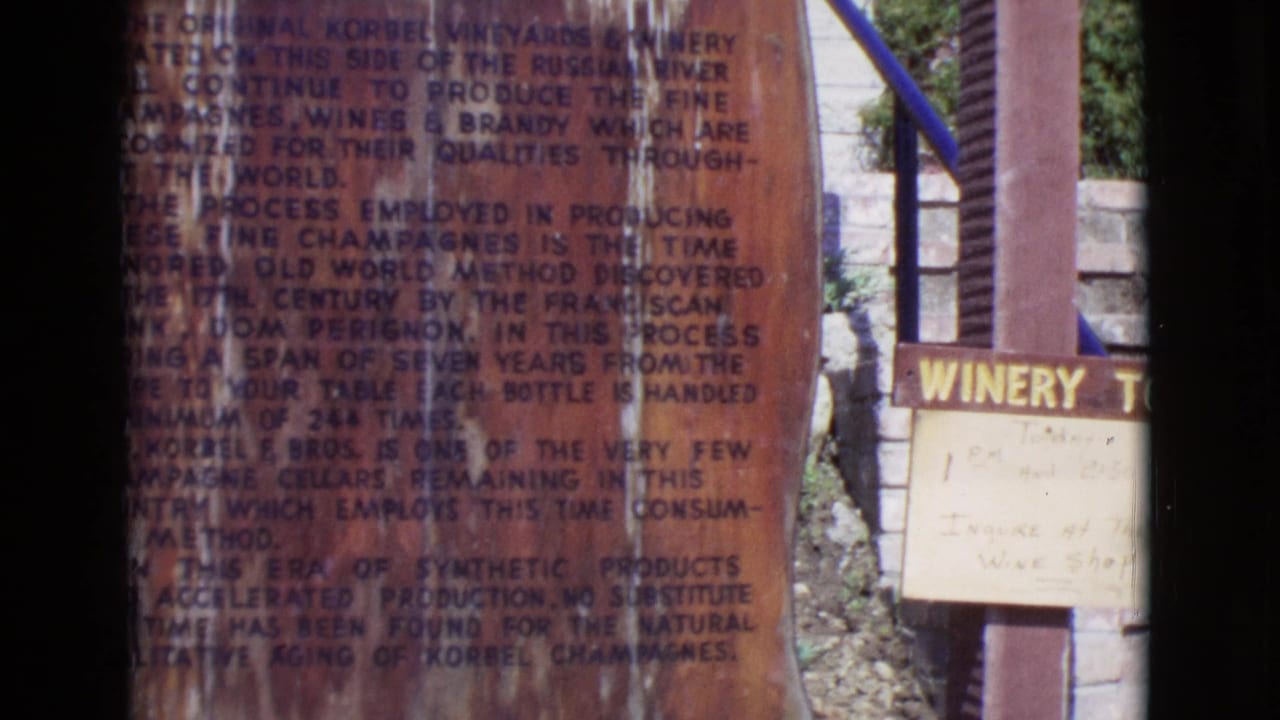 Weathered wooden winery plaque with dense printed text and partial winery sign at right.