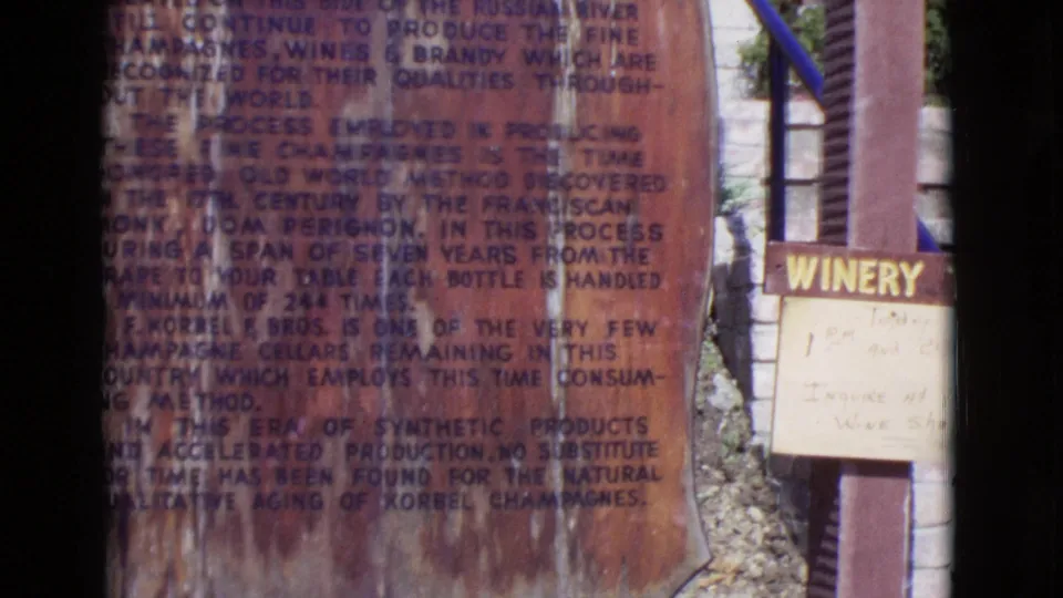 1968 San Diego County 8mm frame showing plaque lettering with a cropped WINERY sign and small handwritten notice to the right.