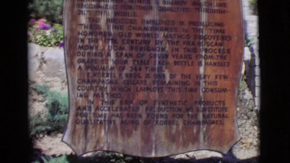 1968 San Diego County 8mm frame showing the full weathered winery plaque, with printed history text and landscaping behind.
