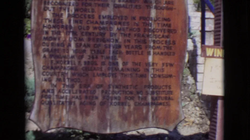1968 San Diego County frame of a brown explanatory winery sign, with partial Korbel-related text and a white winery sign nearby.