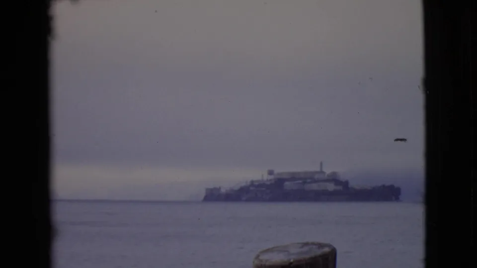 1968 San Diego County 8mm frame showing a large distant ship or vessel across calm water in a hazy coastal view.