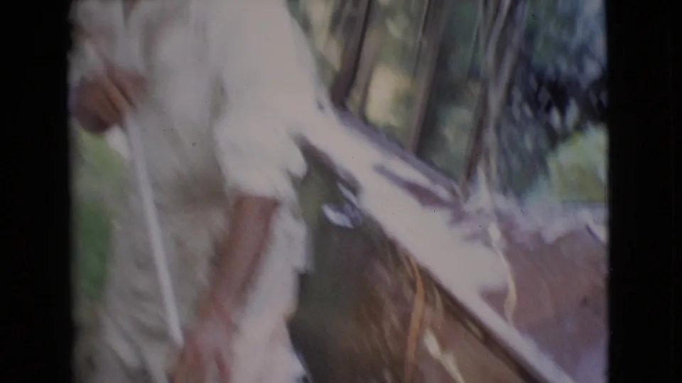 A soft, motion-blurred 8mm frame shows the man close to the dark car as soap and reflections cover the side and windshield.