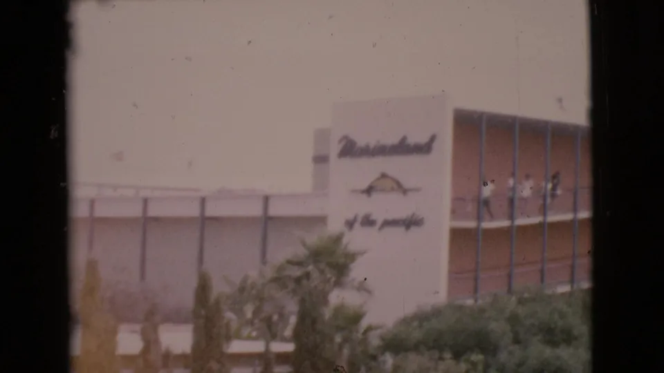The Marineland of the Pacific exterior appears with its sign, glass-fronted building, landscaping, and several balcony visitors.