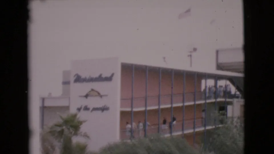 1968 San Diego County 8mm frame showing the Marineland sign and penguins near a bright blue pool at a marine attraction.