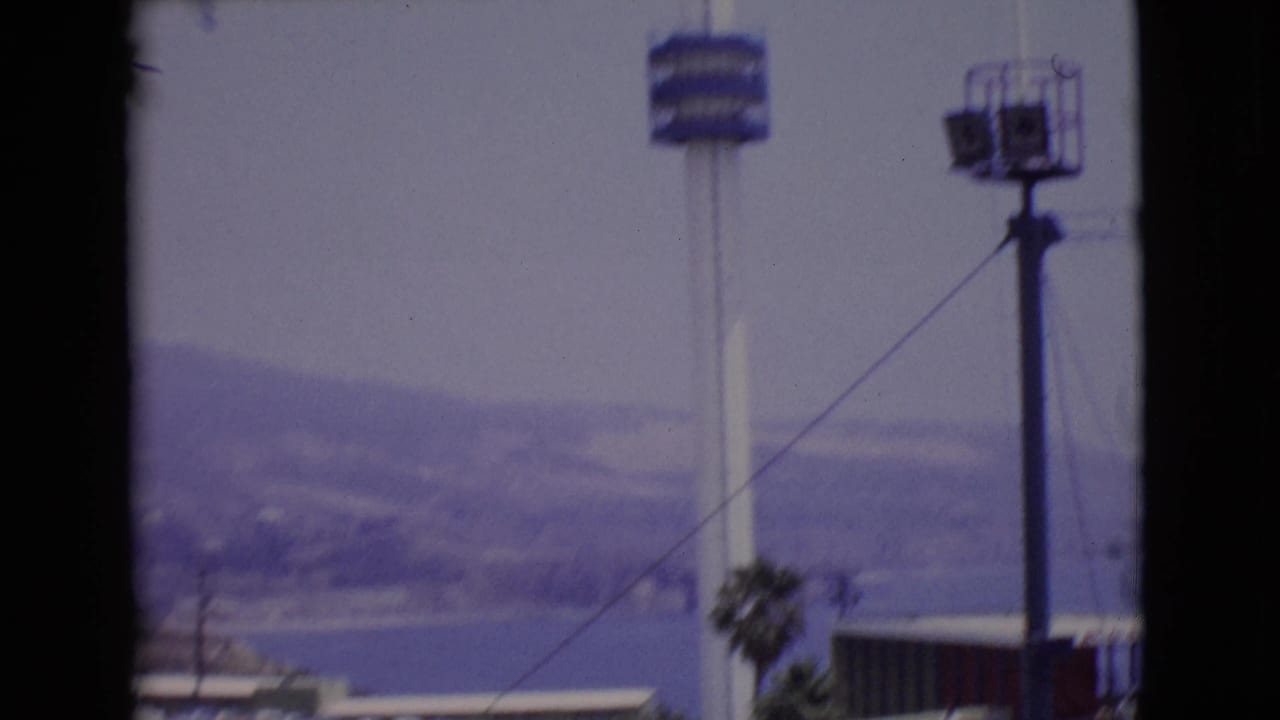 American flagpole and blue observation tower platform against hazy hills and water.