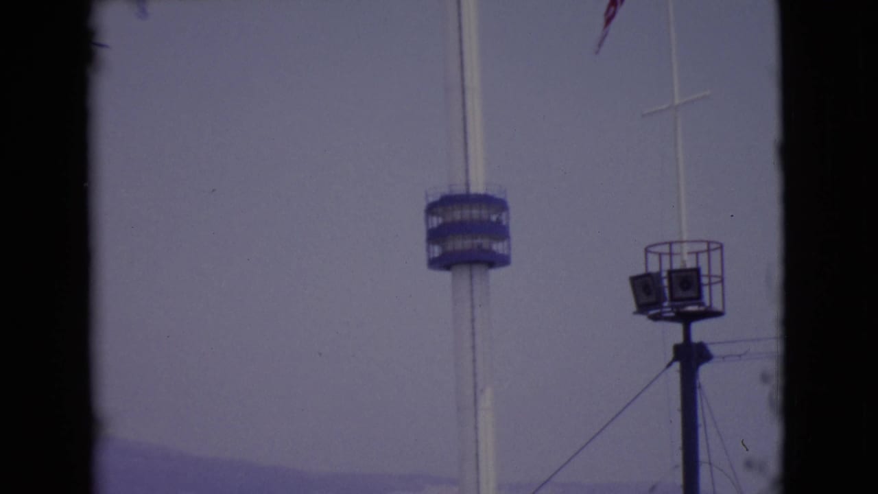 1968 San Diego County frame with a tall white pole, blue circular platform, raised speaker or light stand, and hazy sky.