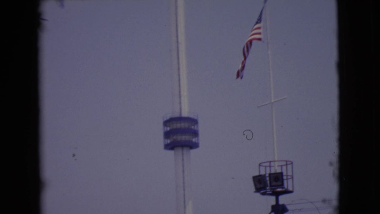 1968 San Diego County frame with the American flag waving near a white pole, blue tower platform, and raised equipment stand.