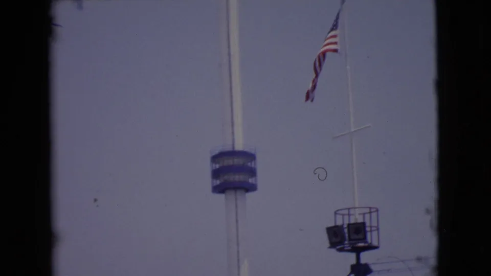 1968 San Diego County frame with the American flag waving near a white pole, blue tower platform, and raised equipment stand.