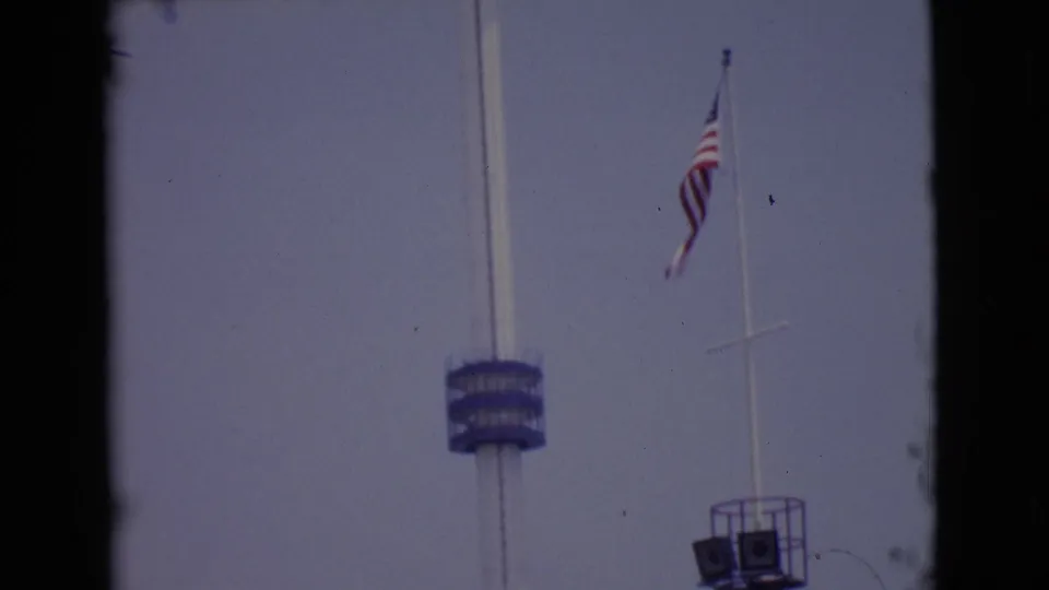 1968 San Diego 8mm frame showing a tall white pole with a blue deck and an American flag on a separate flagpole.