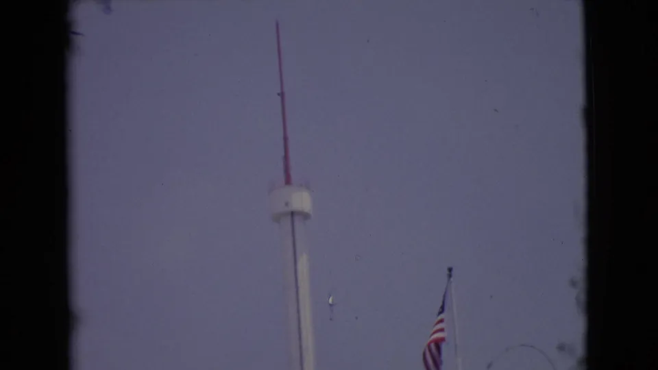 1968 San Diego frame showing the pole rising to a red antenna top, with the American flag lower at right.