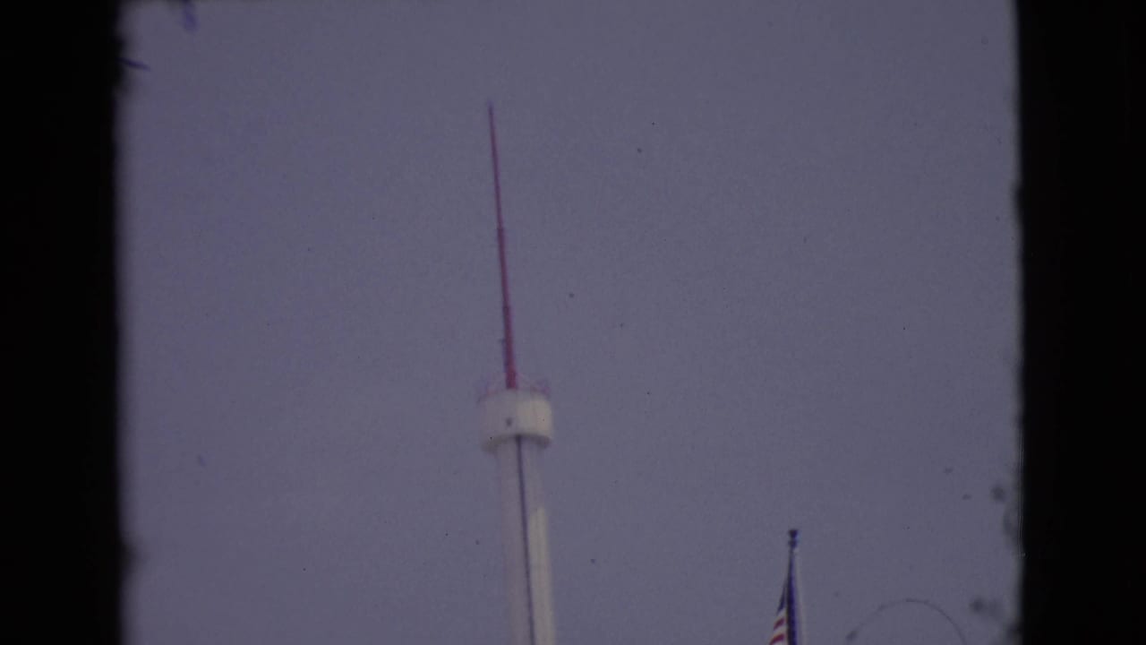 End of the upward pan with the red-tipped pole high in view and an American flag lower to the right.