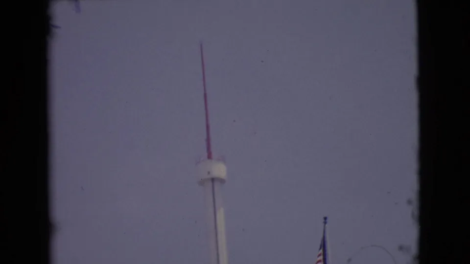 End of the upward pan with the red-tipped pole high in view and an American flag lower to the right.