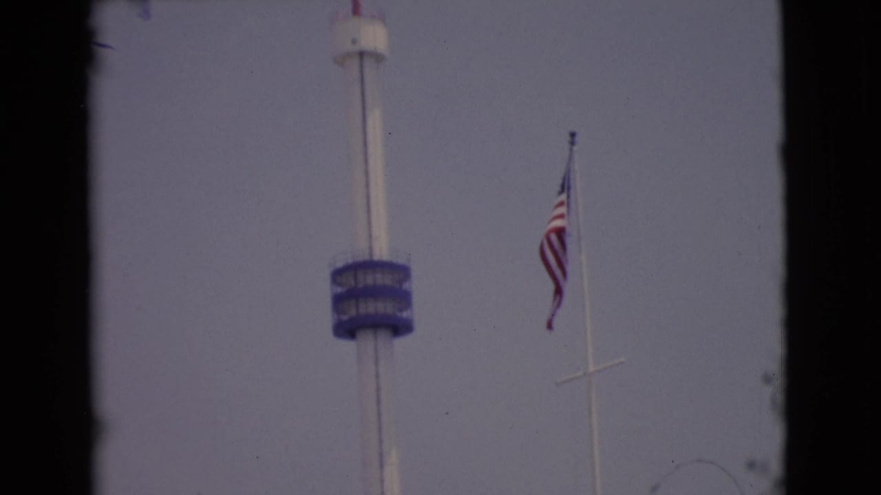 1968 San Diego County 8mm frame with a tall white tower, blue observation deck, and American flag on a nearby pole.
