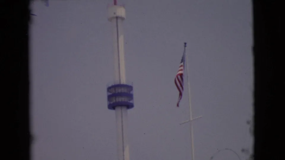 1968 San Diego County 8mm frame with a tall white tower, blue observation deck, and American flag on a nearby pole.