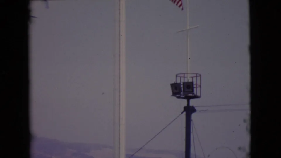 1968 San Diego County 8mm frame with the tower, flagpole, distant hills, and a small elevated platform or light structure.