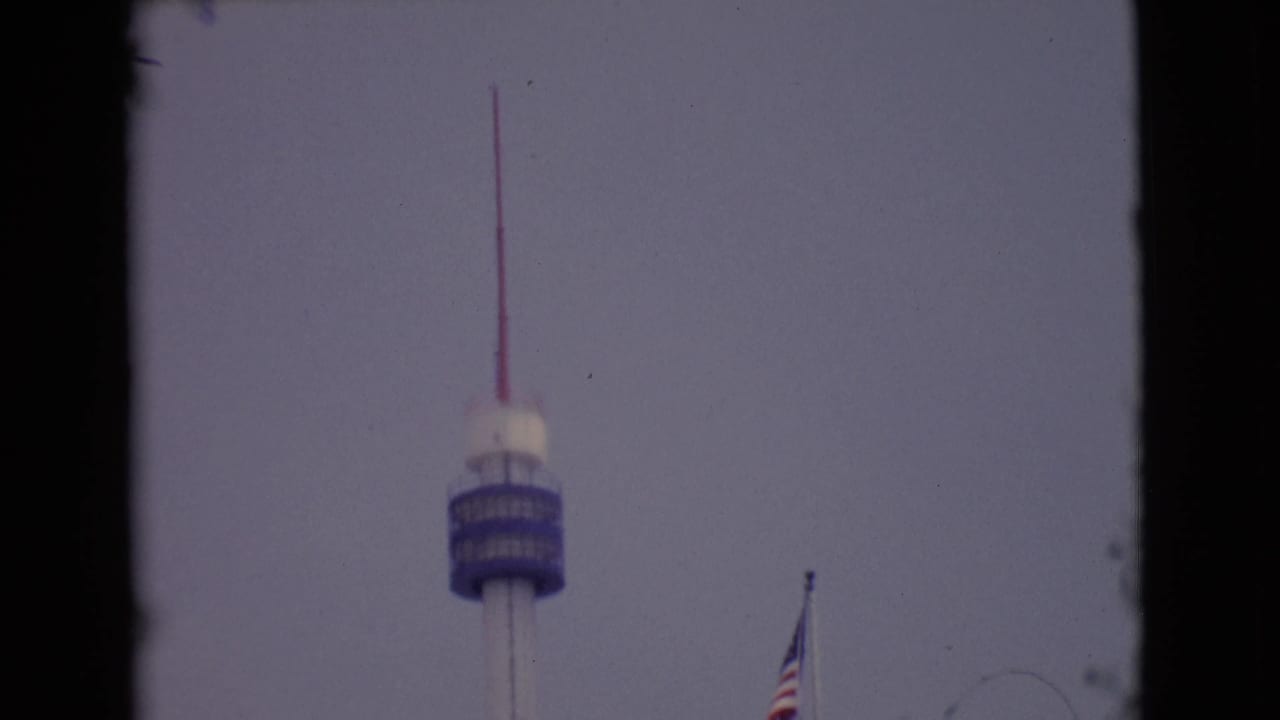 1968 San Diego-area 8mm frame showing the tower centered low in the view with a flagpole near the right side.