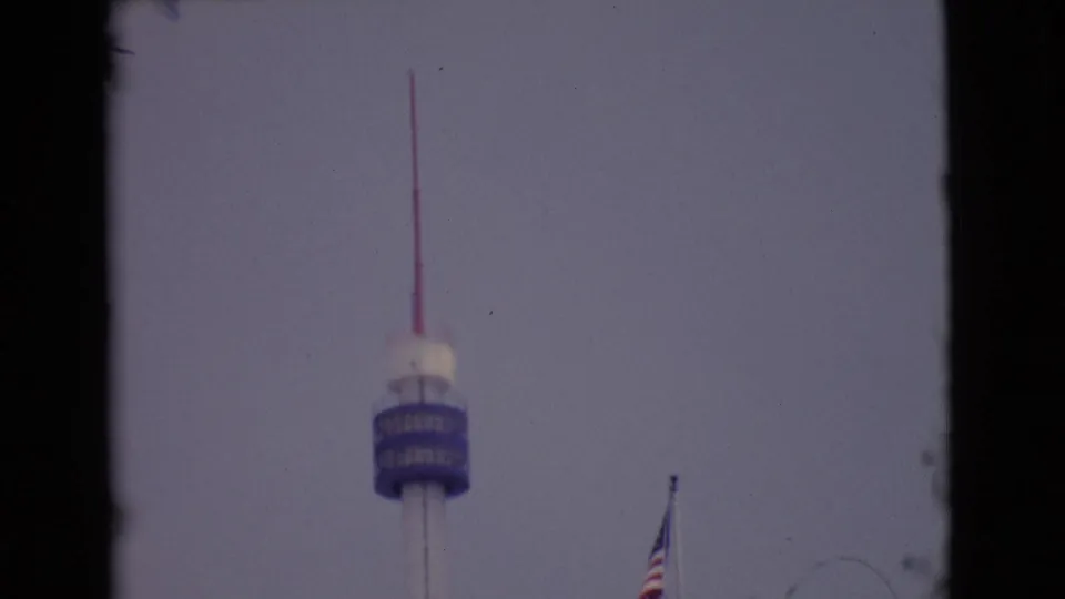 1968 San Diego-area 8mm frame showing the tower centered low in the view with a flagpole near the right side.