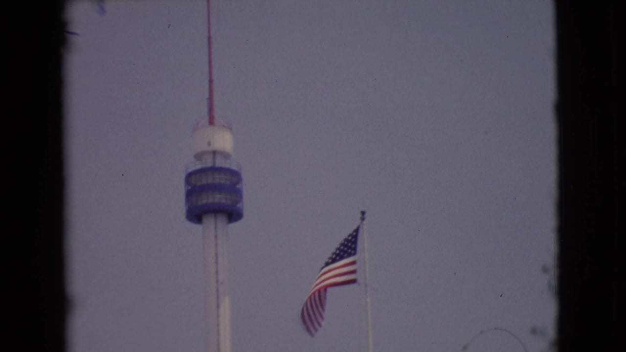 1968 San Diego-area 8mm frame with the blue-deck tower and a U.S. flag waving beside it.