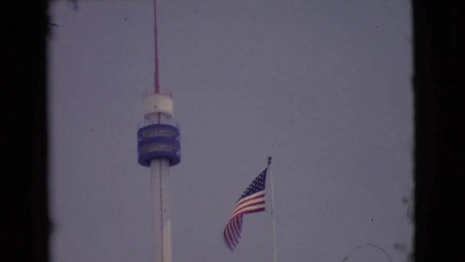 1968 San Diego-area 8mm frame with the blue-deck tower and a U.S. flag waving beside it.