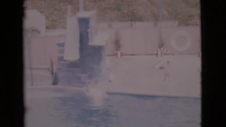 1968 San Diego County 8mm frame showing a seal splashing in the pool near the show platform and barrier signage.
