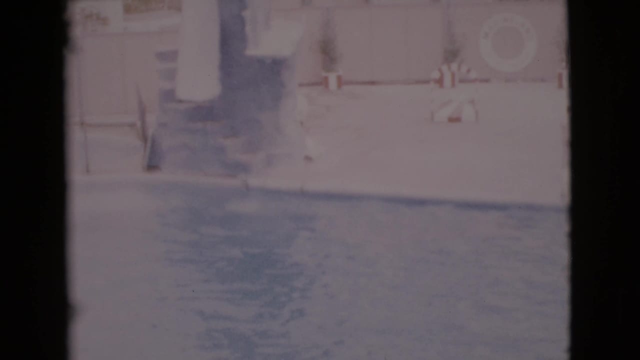 Overexposed pool enclosure with a high platform, wall, steps, and life preserver.