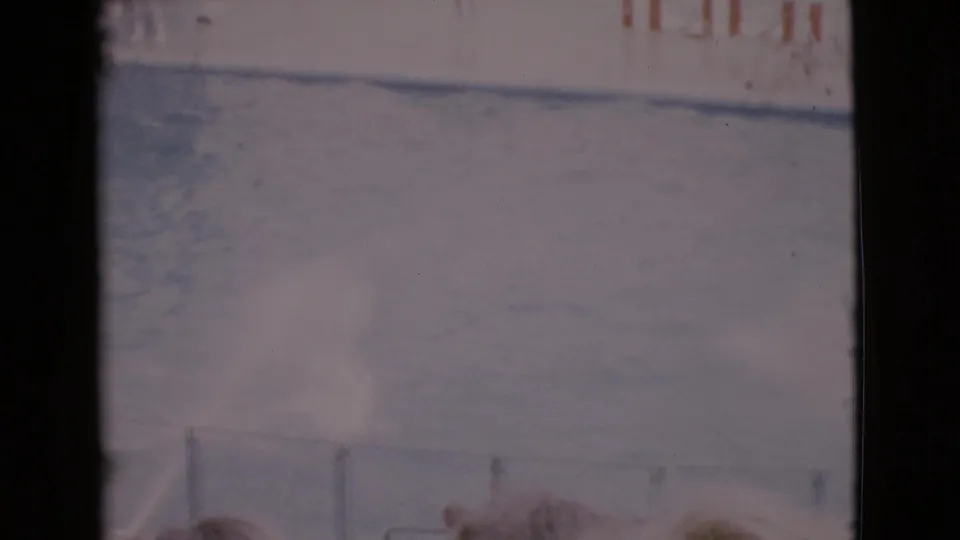 1968 San Diego County home-movie frame showing a sunlit marine show pool with railings and faint signage in soft, faded color.