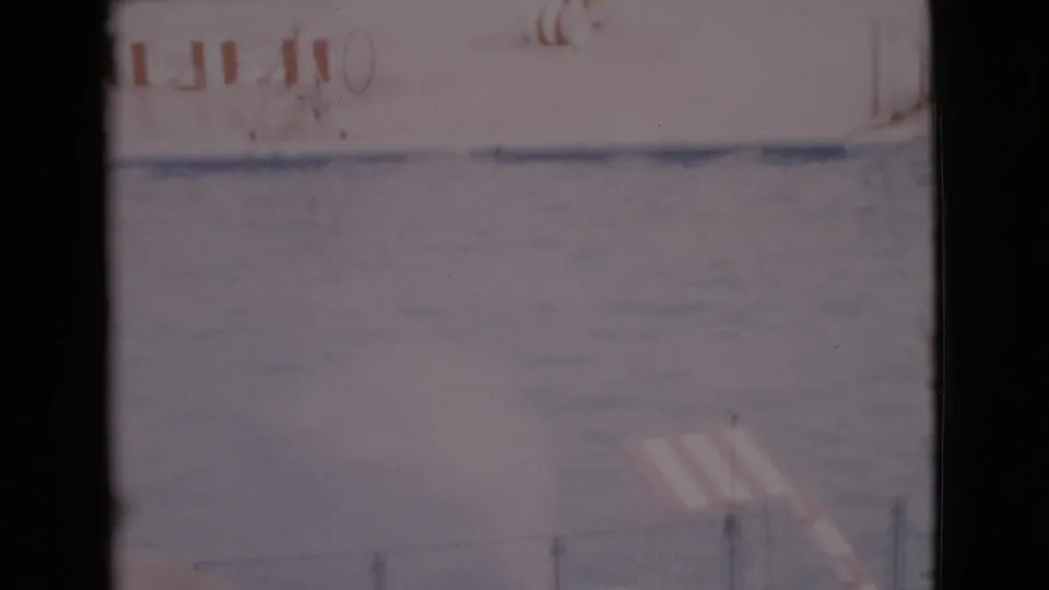 Visitor-shot 1968 frame showing the aquatic show pool, poolside structures, partial signage, and washed-out 8mm color.