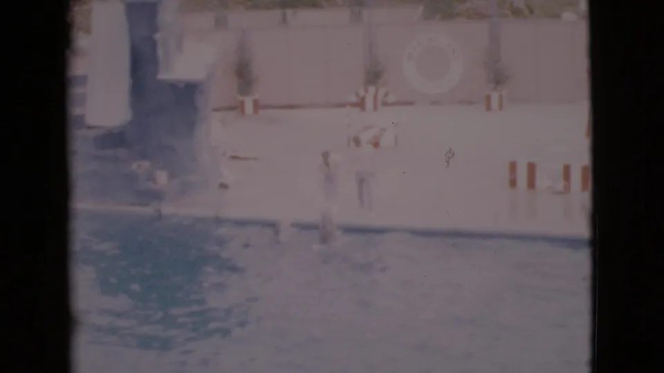 1968 San Diego County marine show frame with people near the pool, a circular poolside sign or target, and faded home-movie exposure.
