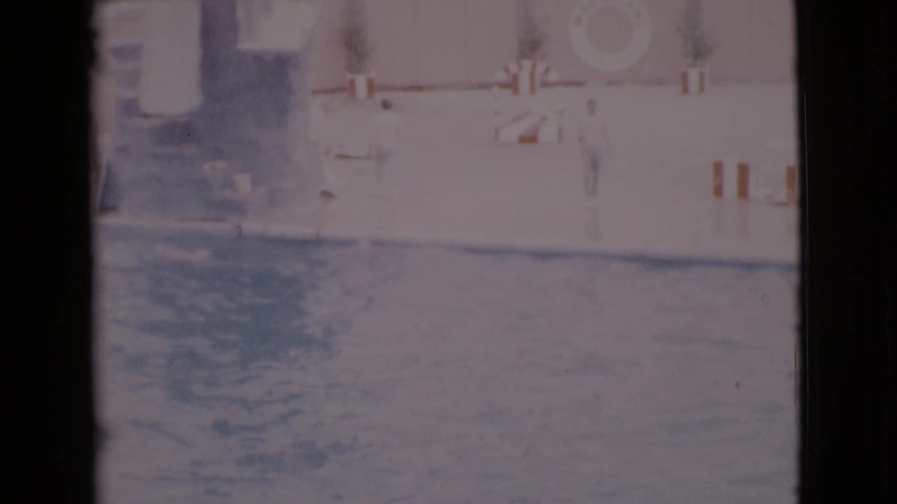 Faded frame of a marine show pool with rippling water and poolside barriers.