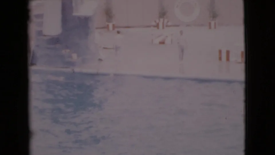 1968 San Diego County 8mm frame showing rippling water in a marine show pool with poolside barriers and structures beyond.