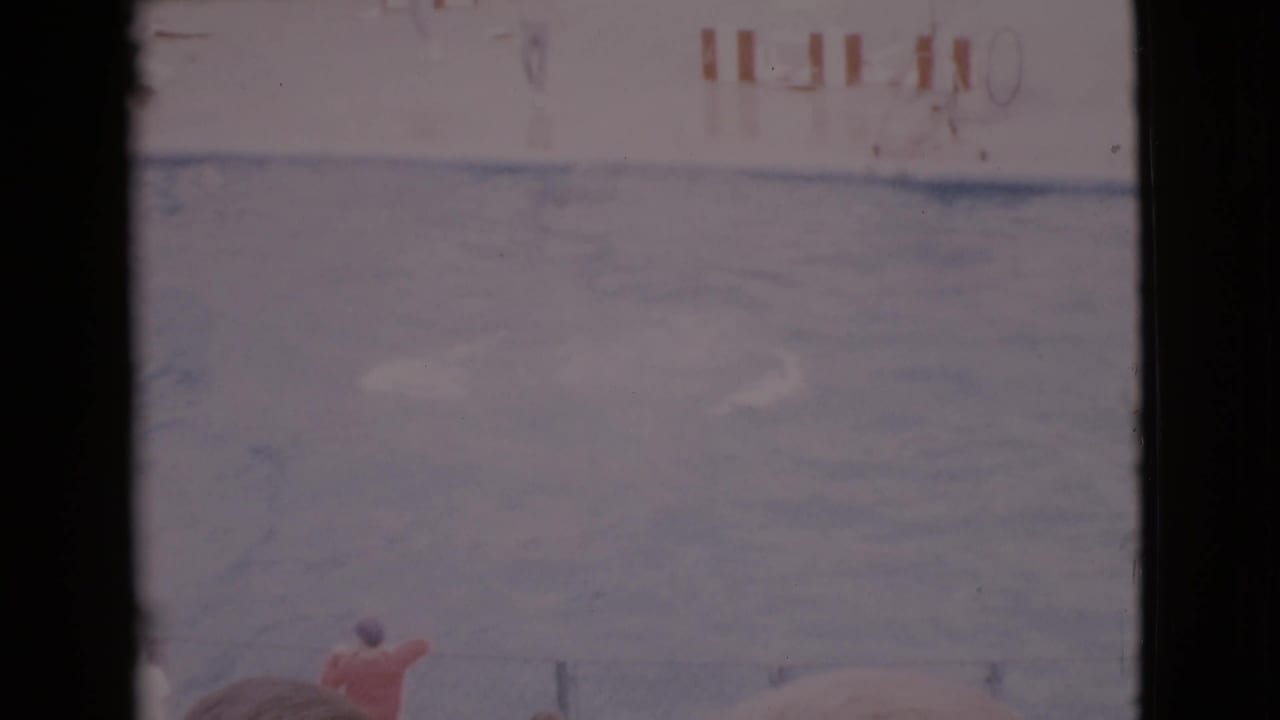 Faded pool scene with a person in red near the water and striped barriers beyond.