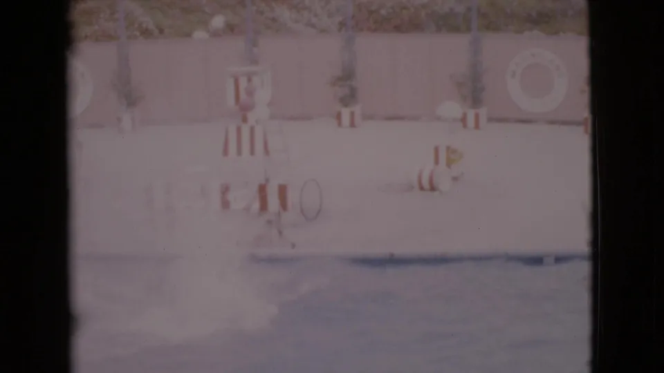 1968 San Diego County 8mm frame showing the aquarium deck, striped barriers, a life ring and the pool edge.