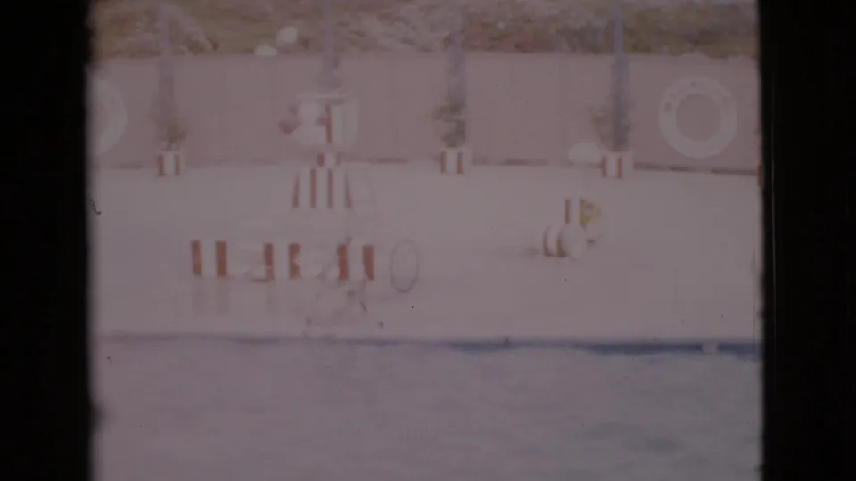 1968 San Diego County pool frame with water in the foreground, a striped stand, life ring, potted plants, and a faint person near the wall.