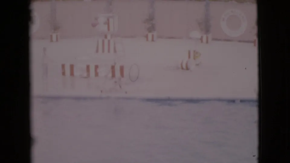 1968 San Diego County 8mm frame showing a marine show pool, striped barriers, pale wall, and life preserver.