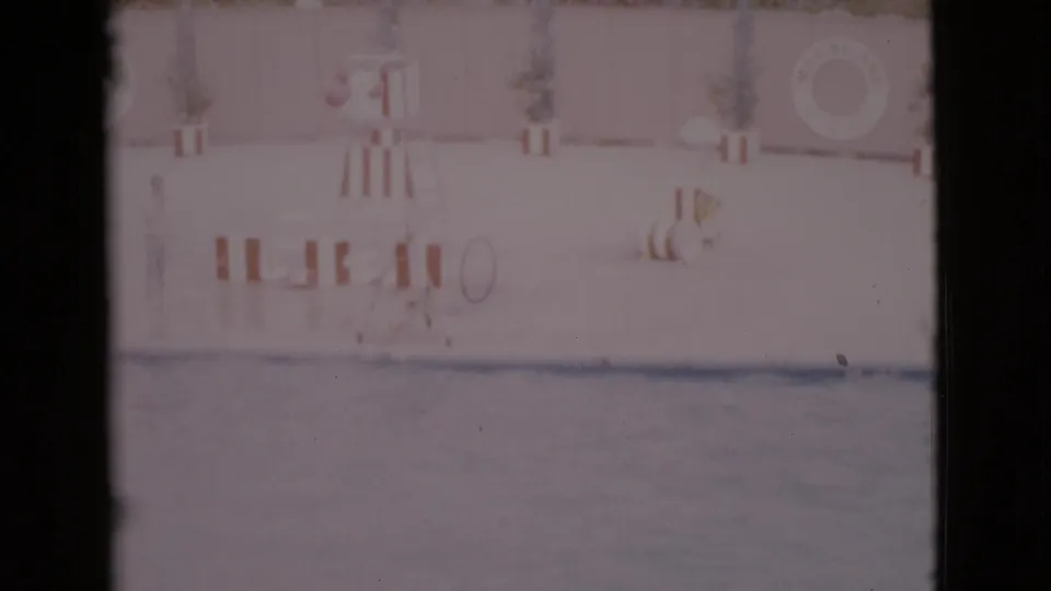 1968 San Diego County home-movie frame of a poolside marine show area with barriers and a life preserver.