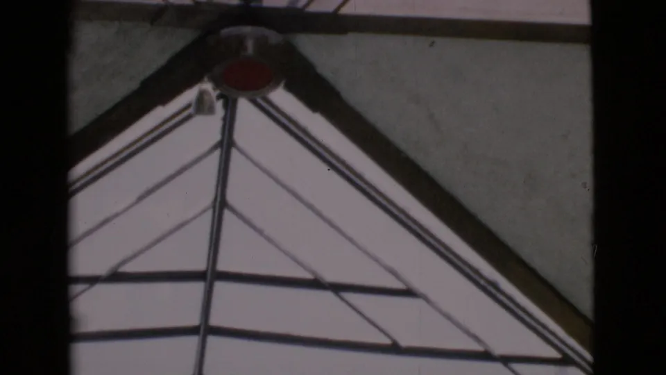 Upward 1968 San Diego County view of geometric glass roof framing and a red circular detail at the top.