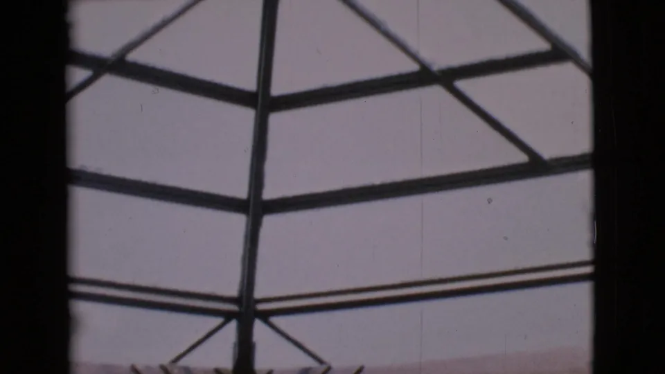 San Diego County 1968 home-movie frame of a glass ceiling grid, dark roof ribs, and faded color from 8mm film.
