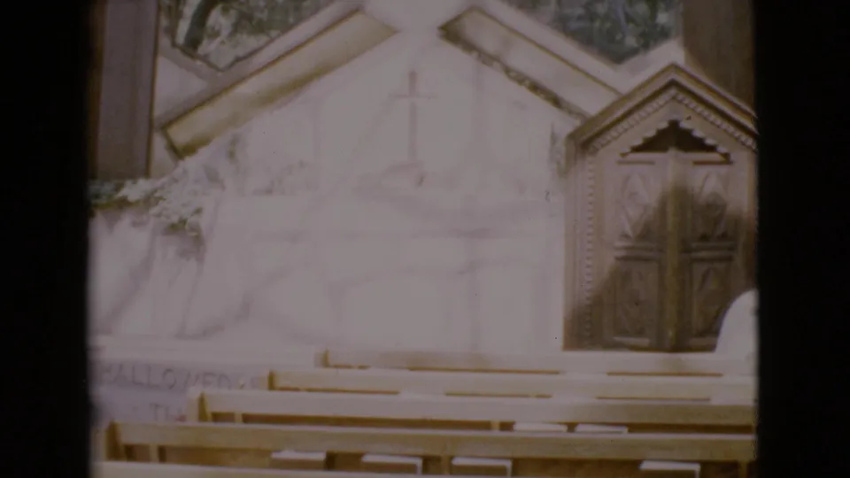 1968 San Diego County church view with rows of pews, an altar wall, a cross, and ornate wooden doors.