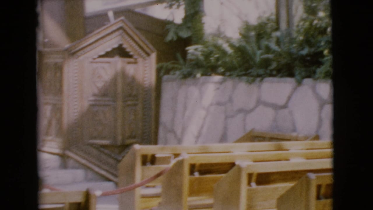 Wooden pews and carved pulpit inside an open-air chapel.