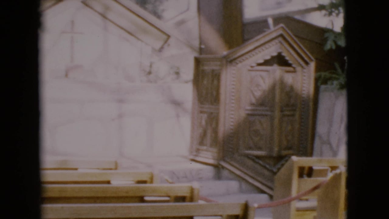 Chapel pulpit beside pews with pale stone wall behind it.