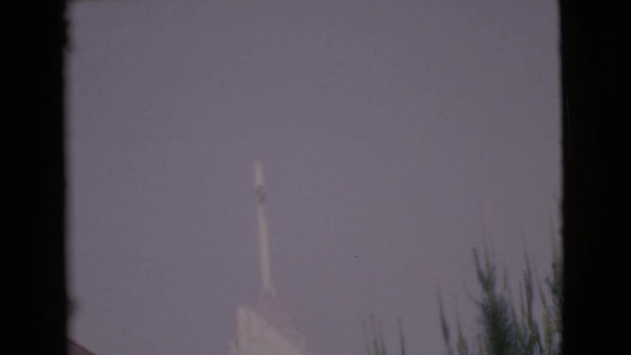 A pale church steeple appears against a hazy sky in 1968 San Diego County 8mm footage.